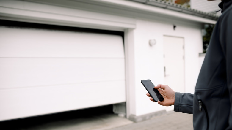 Person holding a smartphone outside a garage