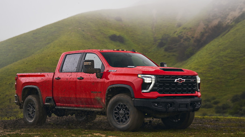 A 2024 Chevrolet Silverado ZR2 Bison in red, front 3/4 view, muddy trail