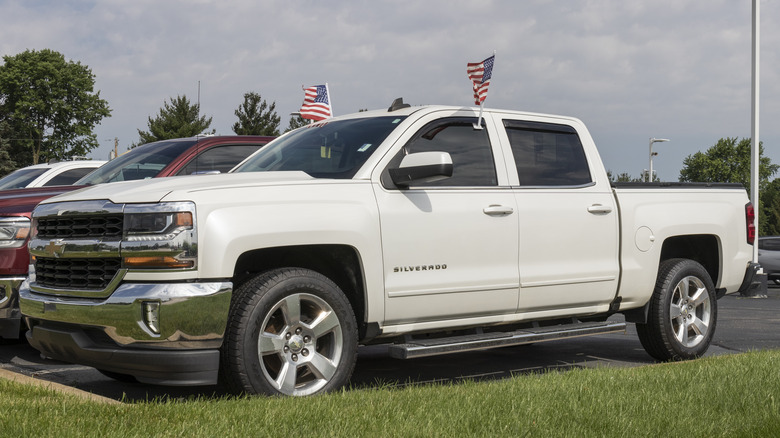 A third generation facelift Silverado in white on a dealership parking lot, front 3/4 view