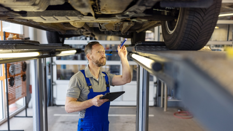 Mechanic inspecting a car on the lift at a body shop