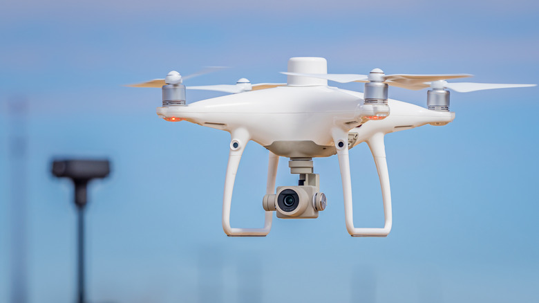 White drone with camera attachment flying in the air