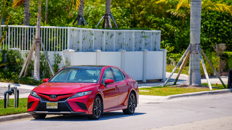 Red Toyota Camry driving down road