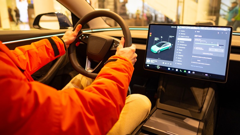 close up male hands on steering wheel in a Tesla model 3