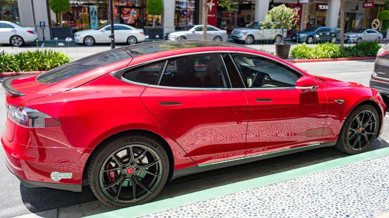 A red Tesla Model 3 parked on the street