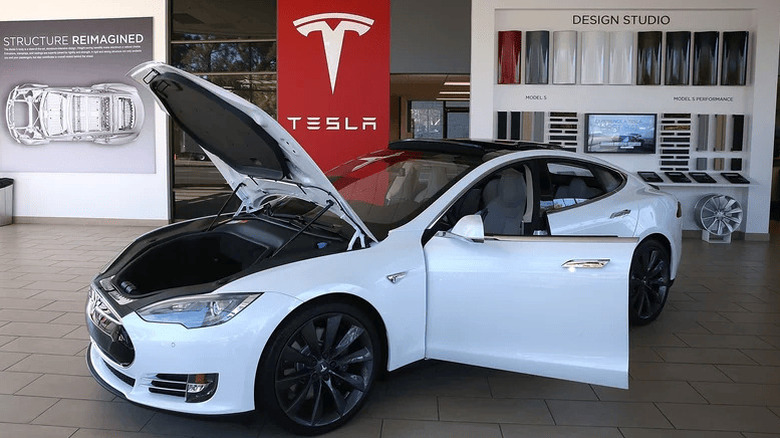 A white tesla model 3 with opened trunk and doors