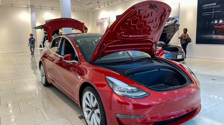 A red Tesla model 3 with opened front and rear trunk