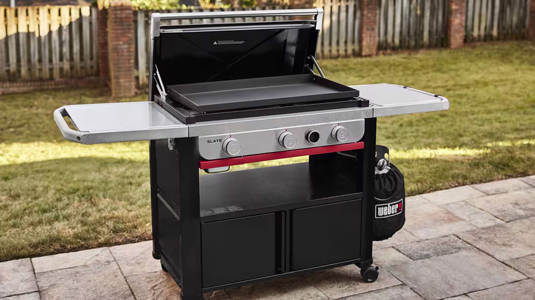 A Weber grill with a griddle plate on a patio