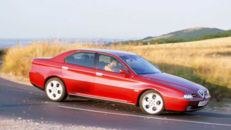 An Alfa Romeo 166 in red on a country road, front 3/4 view