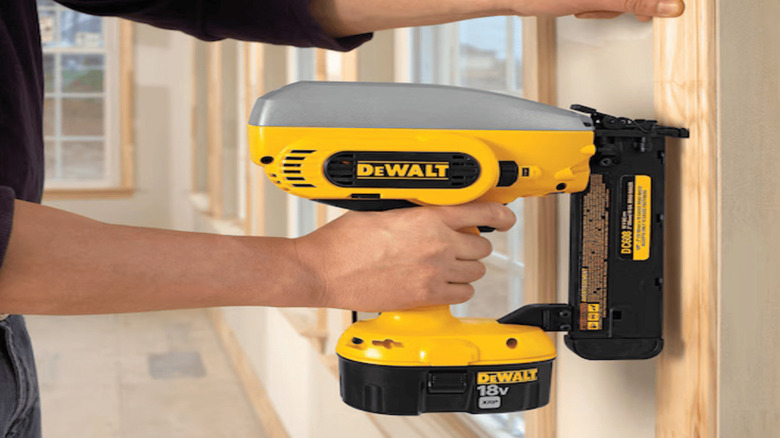 Dewalt's 18V Cordless Brad Nailer fastening wooden molding into a wall