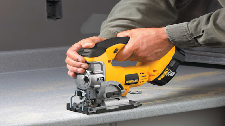 A pair of hands holding a Cordless Jig Saw (DC330B)