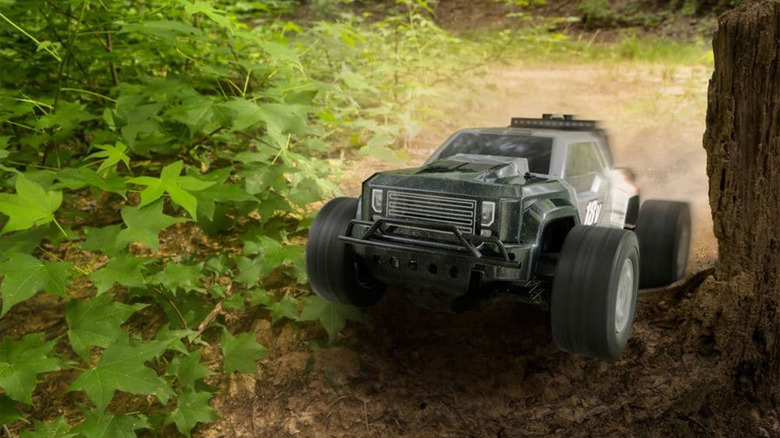 A photo of a Ryobi RC truck driving over a tree root