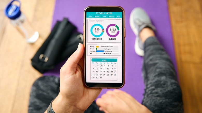 Close Up Of Woman With Smart Watch About To Exercise Looking At Fitness App On Mobile Phone