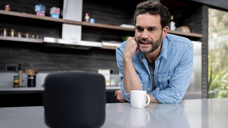 man speaking to a smart speaker in a kitchen