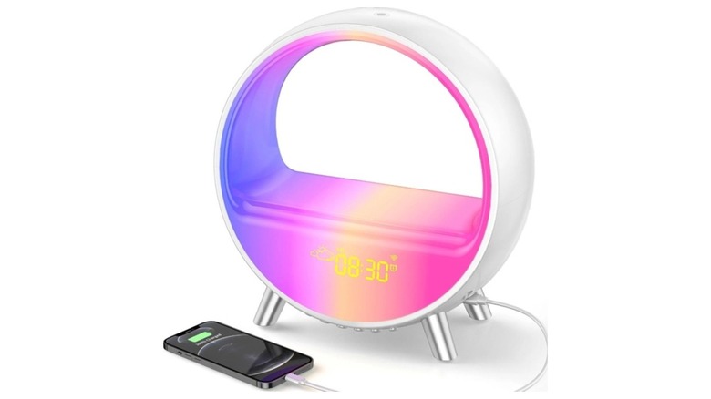 Round white device displaying a sunset glow next to a bed