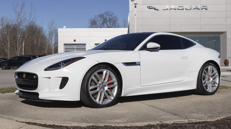 A Jaguar F-Type Coupe in white outside a dealership, front 3/4 view