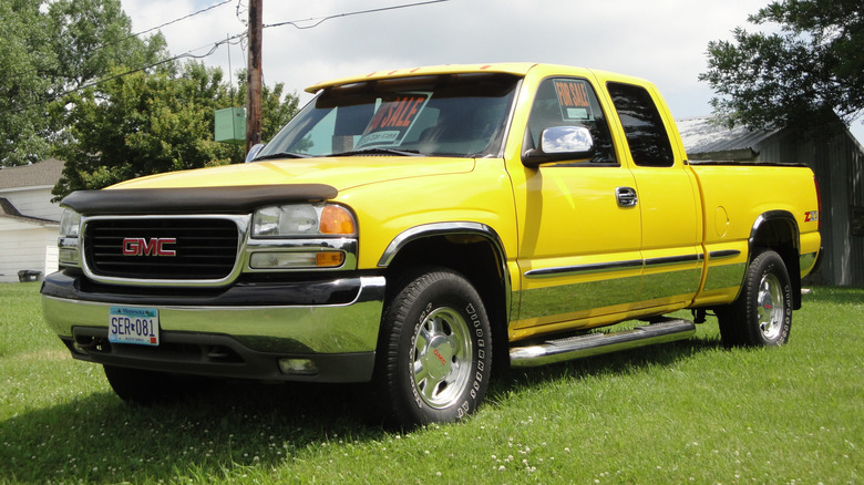 Yellow 2001 GMC Sierra parked on grass