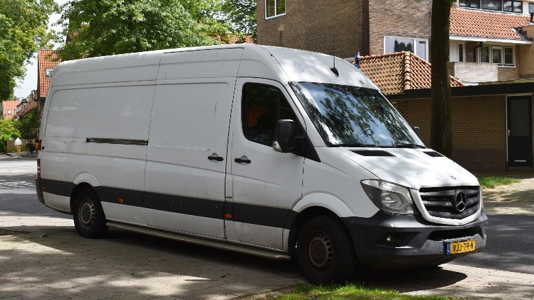 a white Mercedes-Benz Sprinter by the sidewalk of a street