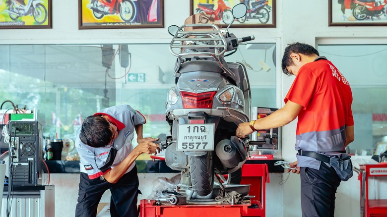 two mechanics working on a Yamaha motorcycle in a repairshop