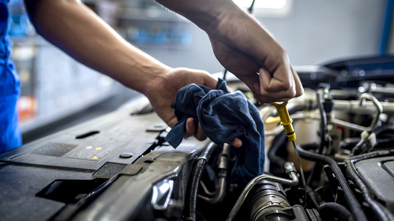 Male mechanic measuring the oil level of an engine at an auto shop