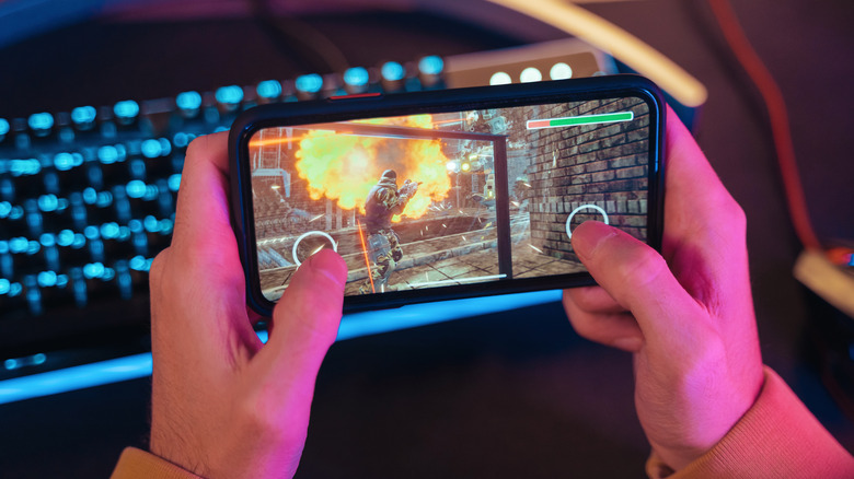 A man is playing a video game on his mobile phone