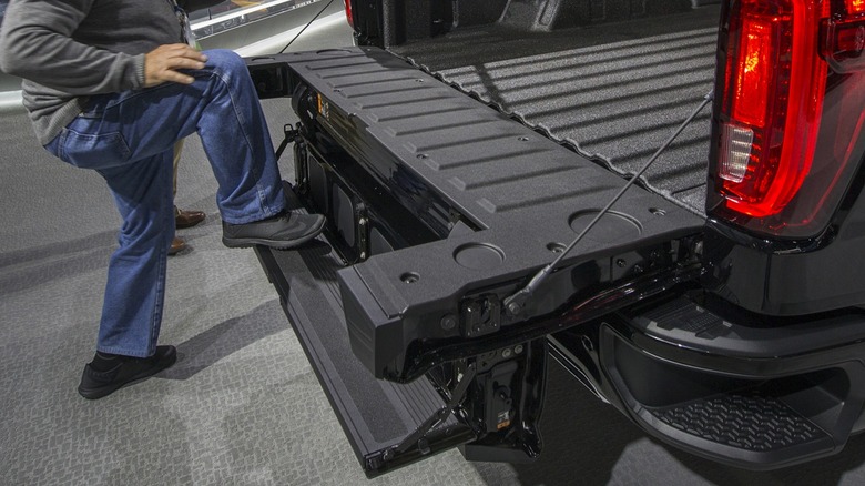 Man stepping on unfolded GMC Sierra tailgate