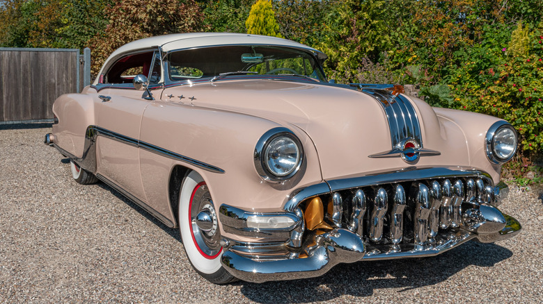 A tan Pontiac Starchief in a gravel driveway