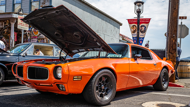 An orange Pontiac Firebird parked on a city street