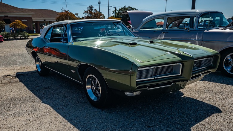 A green Pontiac GTO in a gravel parking lot