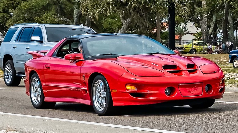 A red Pontiac Firebird driving in traffic