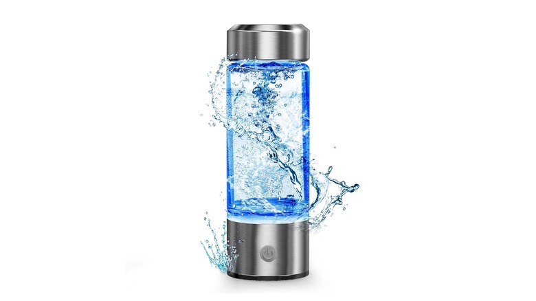 Blue illuminated glass bottle with splashes of water surrounding it