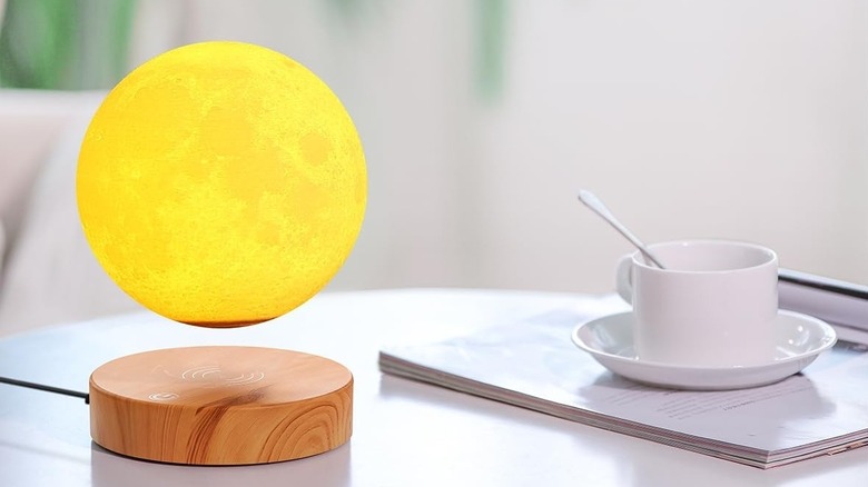 Yellow moon ball floating above a wood base on table