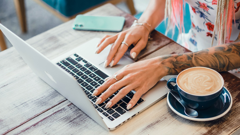 Woman using computer with coffee