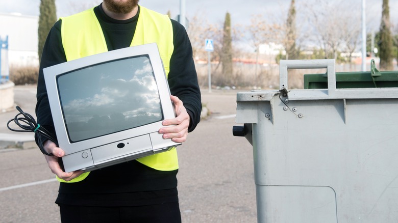 man holding tv garbage bin