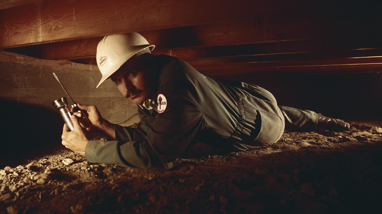 Person under floor using torch