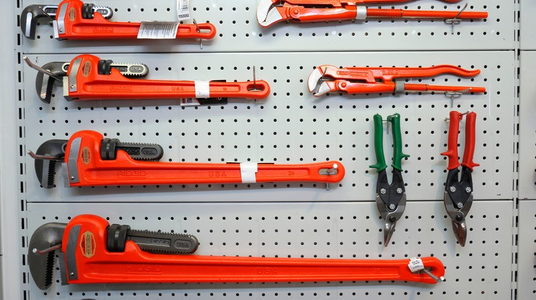 Collection of orange pipe wrenches on a pegboard display