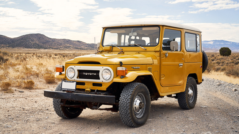 Yellow 1977 Toyota Land Cruiser FJ40 parked on a gravel trail front 3/4 view