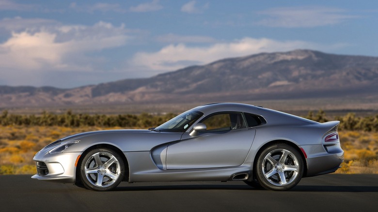 a grey Dodge Viper parked on a road in front of some mountains