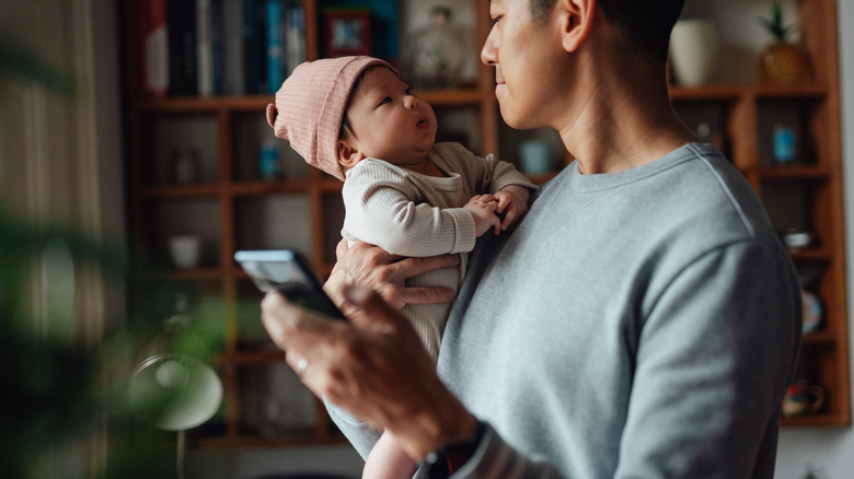 father holding baby and phone