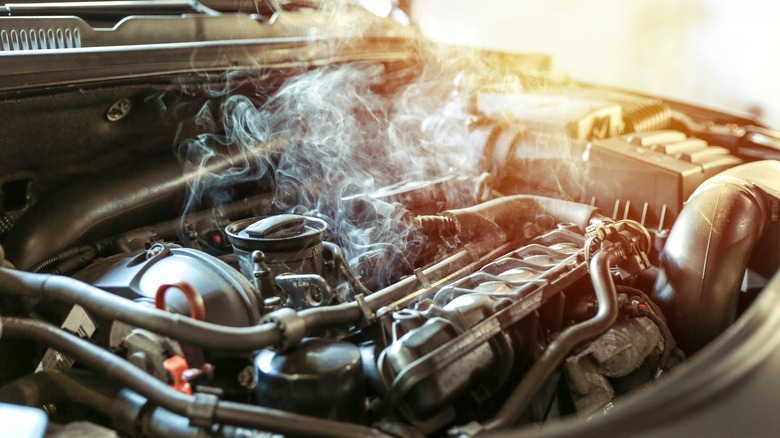 a car engine with visible smoke emanating, indicating it is overheated or malfunctioning