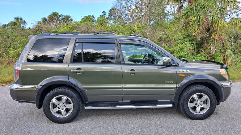 A first generation Honda Pilot parked by trees