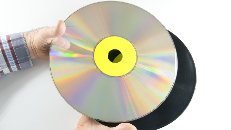 Person holding a LaserDisc next to a vinyl record.