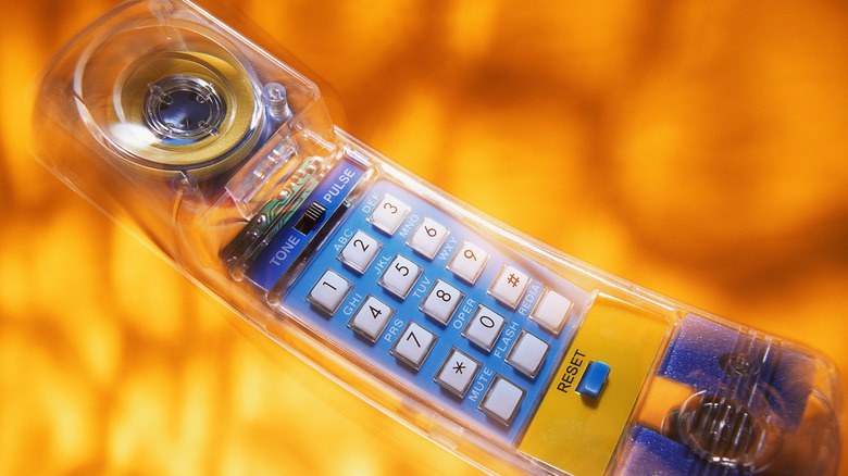 See-through landline phone handset on orange background.