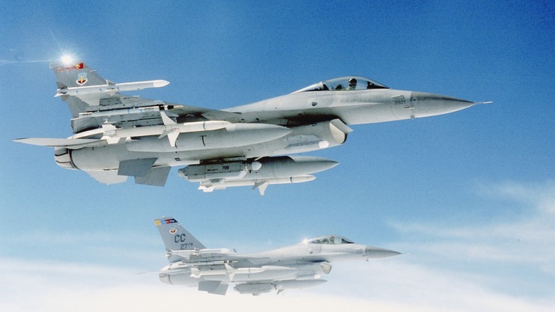 F-16s flying in formation against a blue sky with clouds.