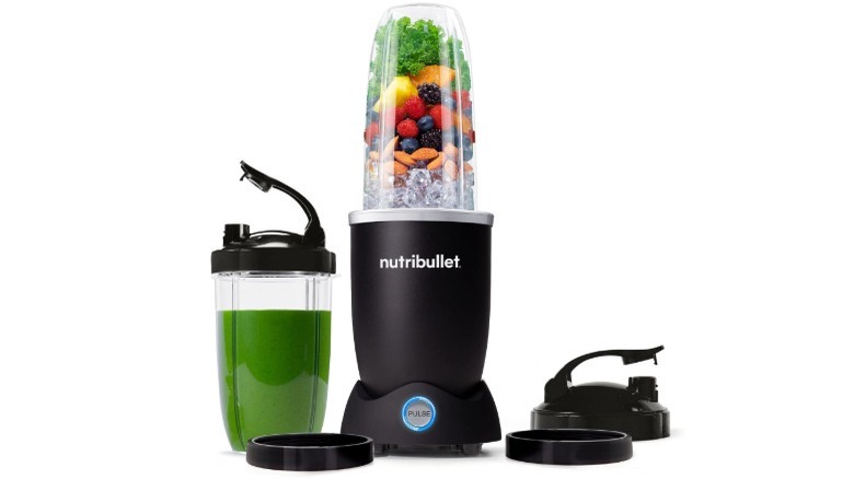 A Nutribullet Pro+ 1200 Blender and a green smoothie against a white background