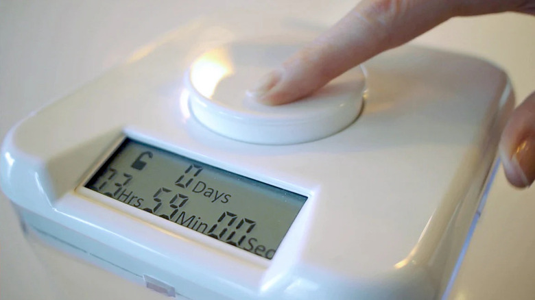 A person presses a button on the Kitchen Safe phone lockbox