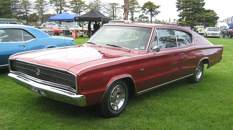 A red 1966 Dodge Charger 426 Hemi parked on grass