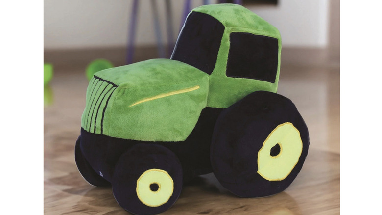 John Deere Tractor Plush Pillow on a wooden floor.