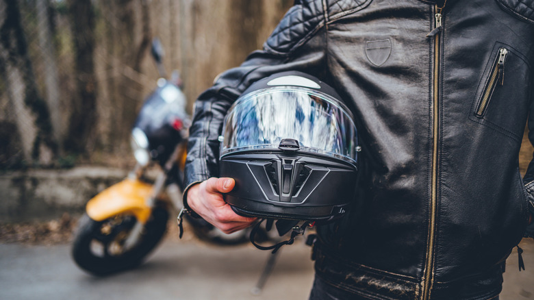 motorcyclist in jacket holding helmet