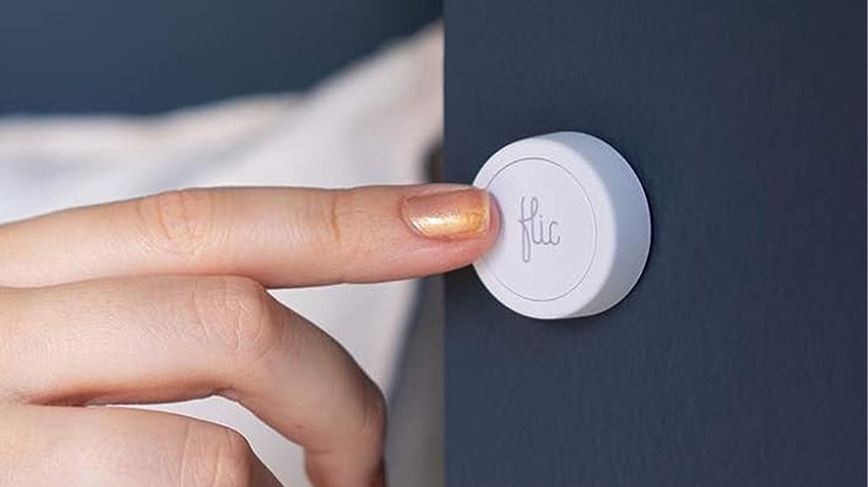 A woman pressing a Flic 2 button on a wall