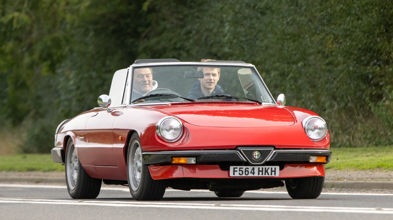 Red Alfa Romeo Spider driving on a road